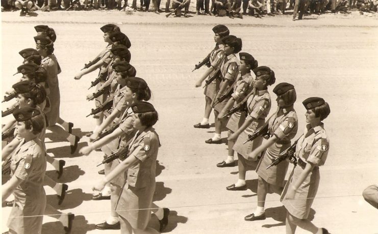 Female Israeli soldiers walking in formation while holding Uzi submachine guns