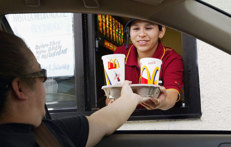 Female McDonald's employee handing a customer their drinks on a tray