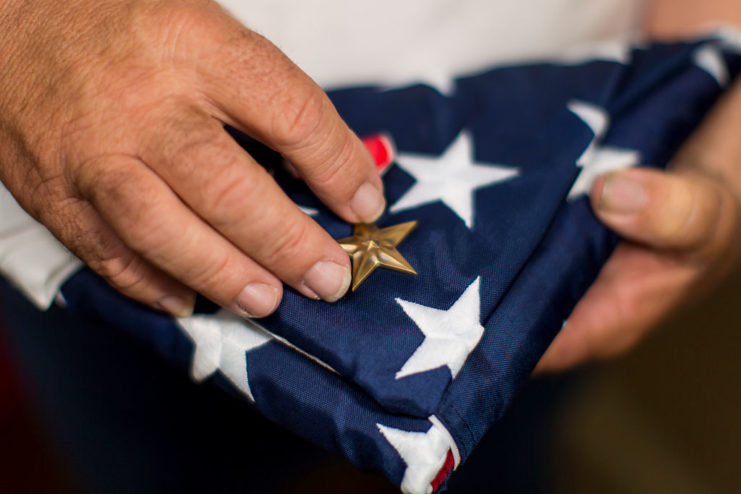 Hands holding a Bronze Star and American flag