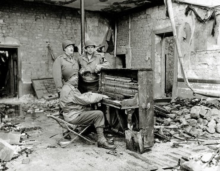 Three soldiers standing around a piano