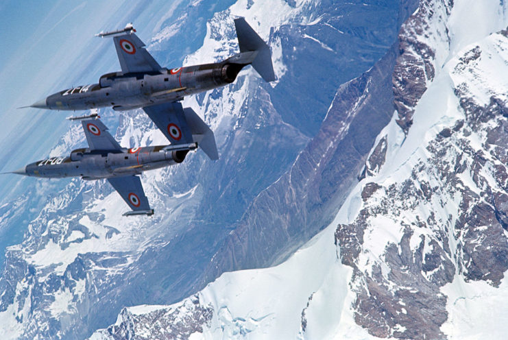 Two F-104 starfighters in flight over a mountain range