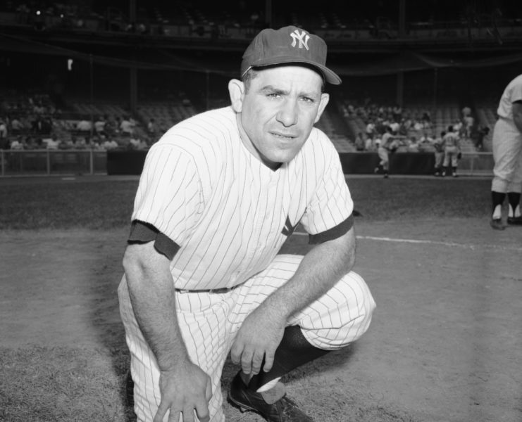 Yogi Berra kneeling in his baseball uniform.