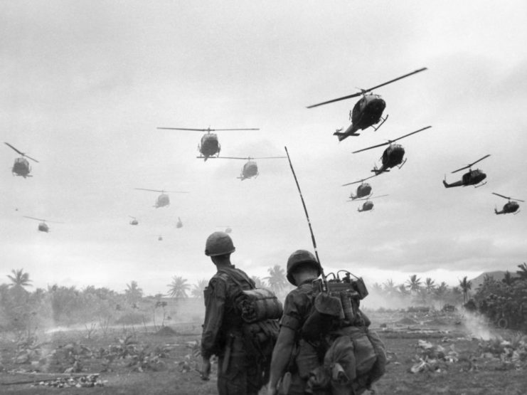 Helicopters flying over two soldiers
