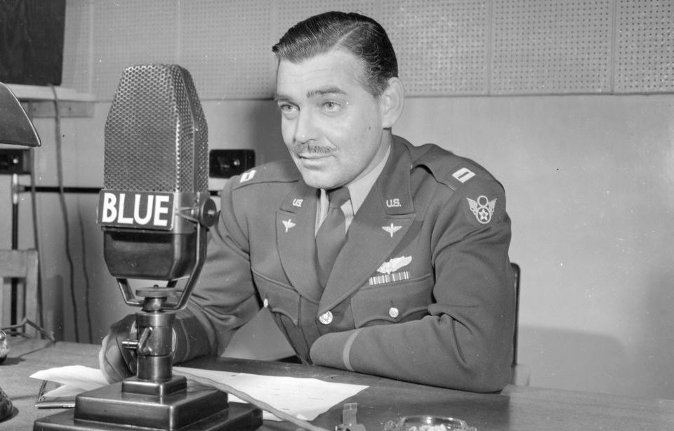 Clark Gable sitting before a microphone