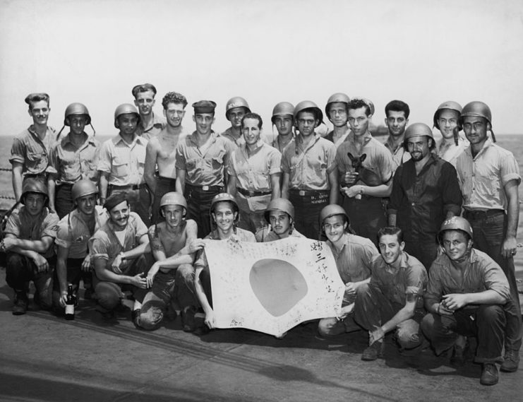 US Coast Guardsmen posing with a captured Japanese flag