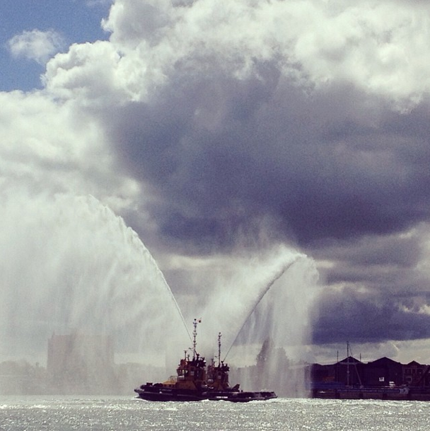 Tug boats spray water cannons as they escort veterans out to sea.