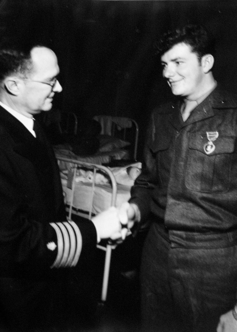 Bud Redel, right, receives a Purple Heart Medal in 1951 while recovering in a naval hospital in Japan. Courtesy of Bud Redel
