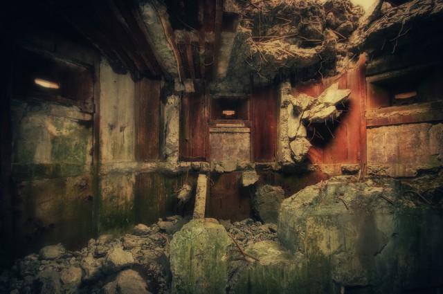 Ruins of a two- storey frontal-firing three-loophole heavy machine gun pillbox. Huge internal explosion has swept the interior clean. The roof (170 cm of reinforced concrete supported by extra heavy beams) is also cracked open; a huge hole is gaping at the sky giving a clue to the power of a shaped charge which had been detonated there.Armored housing for Maxim heavy machine guns are still in place, as well as metal plates lining the walls. They served as a protection from pieces of concrete which could be torn from the walls by heavy shelling – these could easily wreak havoc in the tight interior.There is no floor - it collapsed entirely – and I took the photo standing at the bottom of a lower storey which is normally below ground level.