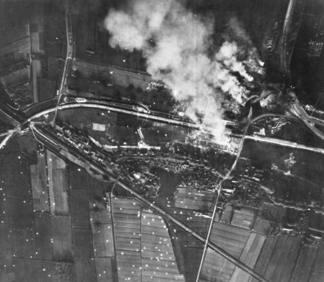 Waalhaven airfield burning as seen from above. Note the white parachutes that litter the area.