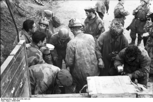 German and Italian soldiers are fed out of the back of a lorry.