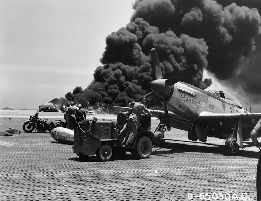 P-51 towed away from B-29 on fire