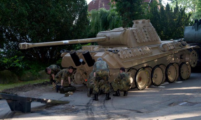 In this July 2, 2015 picture a  World War II -era Panther  tank  is prepared  for transportation from a residential property in Heikendorf,  northern Germany.  Authorities have seized a 45-ton Panther tank, a flak canon and multiple other World War II-era military weapons in a raid on a 78-year-old collector's storage facility in northern Germany. Kiel prosecutor Birgit Hess said the collector is being investigated for possibly violating German weapons laws but his attorney Peter Gramsch told the dpa news agency all the items were properly demilitarized and registered.  (Carsten Rehder/dpa via AP)