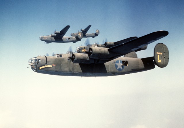 An air-to-air left side view of four B-24 Liberator aircraft in formation. The B-24 was built for World War II combat.