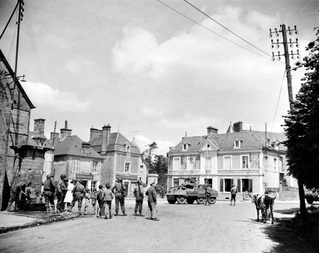 Un groupe de soldats américains dont 4 MP à la fontaine du village entourés par femmes et enfants,le 12 juin à Sainte-Marie-du-Mont. Le GI à gauche nettoie ses gamelles. Le même groupe sur 3 photos : p011591, p011592 et p011594. Sur les façades des bâtiments : BOURRELLERIE, BOUCHERIE E. DESMONTS, l'étage et la fenêtre de toit ont été mitraillés. Le bâtiment derrière le blindé M 8 : Ste MARIE du MONT PTT CAISSE NATIONALE d'ÉPARGNE Un GI est assis sur le Monument aux morts, voir ici: http://www.flickr.com/photos/mlq/4033956673/ Un autre à l'intérieur de la Caisse d'Epargne, fenêtre en bas à droite. Une fermière avec deux vaches normandes. Le même lieu a été photographié le 7 juin avec d'autres personnages voir les p011582 et p011585. Voir ici chez Gettyimages en plan rapproché http://www.gettyimages.com/detail/50703244 Un montage de plusieurs photos avec la même femme Marrie-Esther Duchenes et des paras http://www.flickr.com/photos/mlq/7380088760/in/photostream