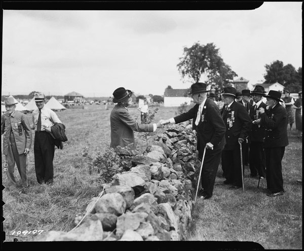 Photograph of Union and Confederate Veterans Shaking Hands Across the Stone Wall at the 1938 "Blue and Gray Reunion" at Gettysburg