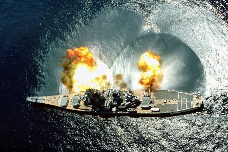 An overhead view of the battleship USS IOWA (BB-61) firing all 15 of its guns (nine 16-inch and six 5-inch) during a target exercise near Vieques Island.  Careful observation of the three main turrets shows the barrels in various states of recoil.
