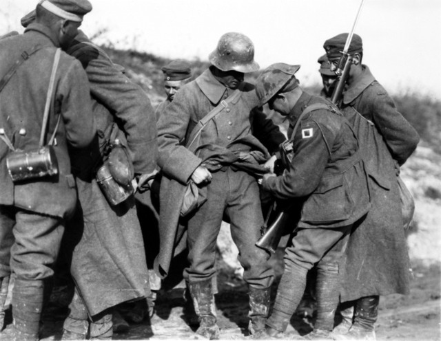 Australian_soldiers_searching_German_POWs_for_souvenirs_in_October_1918