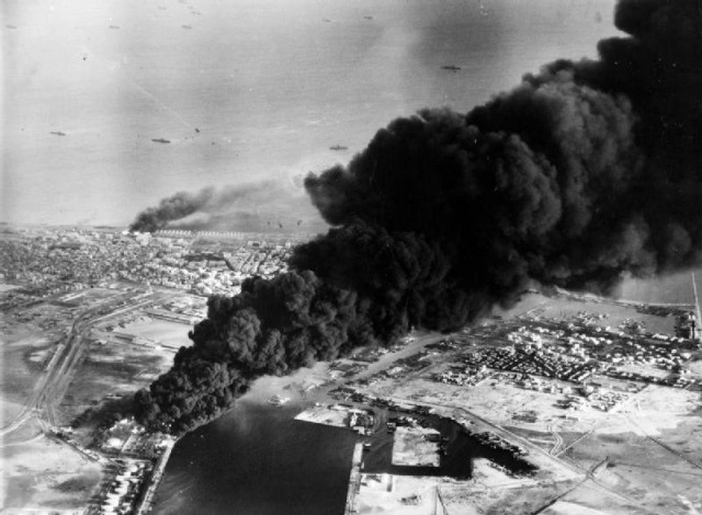 Smoke rises from oil tanks beside the Suez Canal hit during the initial Anglo-French assault on Port Said, 5 November 1956. (Wikipedia)