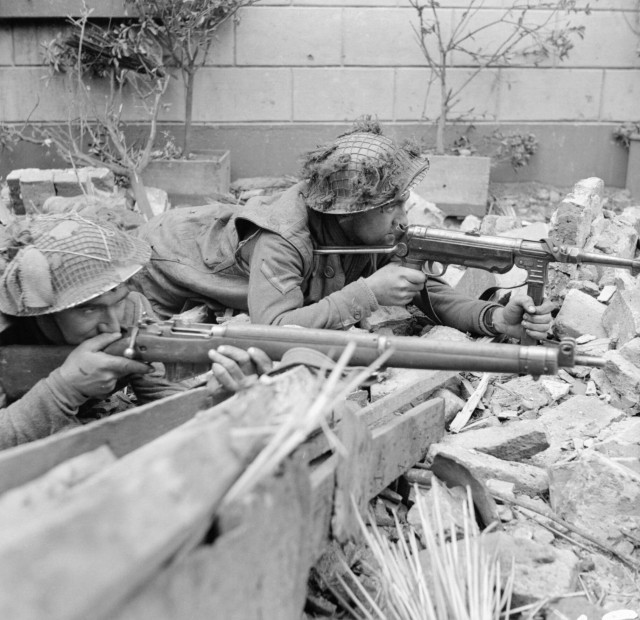 Lance Corporal R. Hearn and Private F. Slater (nearest camera) of the 1st Royal Norfolk Regiment, 3rd Division, aim their weapons in the ruins of Kervenheim, 3 March 1945. Corporal Hearn is using a captured German MP40 'Schmeisser' submachine gun.