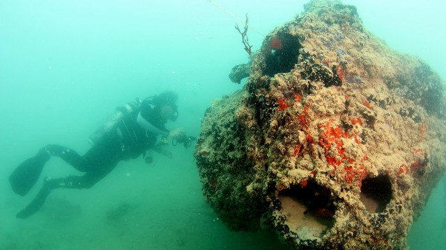 A diver examines the gunner's forward turret on a PBY-5 Catalina resting on its right side in Kāne‛ohe Bay, Hawaii. The plane was sunk during the attack at Pearl Harbor on Dec. 7, 1941. Credit: UH Marine Option Program