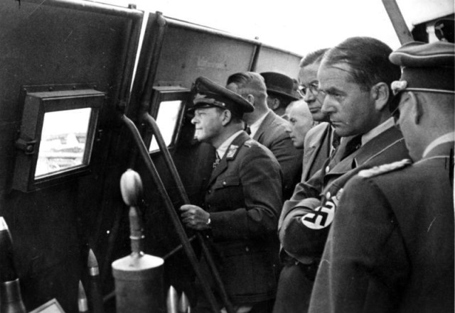 Zentralbild II. Weltkrieg 1939-45 Arbeitstagung der führenden Männer der deutschen Rüstung im Oktober 1943, die der Reichsminister für Rüstung und Kriegsproduktion Prof. Albert Speer einberufen hat. Auf einem Flugplatz im Osten beobachten die Teilnehmer hinter Deckungsschutz die Vorführung eines neuentwickelten Kampfmittels. Links Generalfeldmarschall Erhard Milch, rechts Reichsminister Speer.