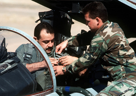 Sgt. Bradley Russell, crew chief, secures Capt. Cesar Rodriguez into the cockpit of a 58th Tactical Fighter Squadron F-15 Eagle aircraft prior to a mission during Operation Desert Storm.