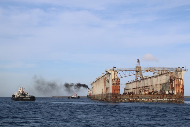 The floating dry-dock “Richland” (ADFM-8) was towed from the confines of Apra Harbor, U.S. Naval Base Guam (NBG), for an open ocean tow from Guam to the Philippines, Jan. 28. The large tug boat, "Rhocas," from the Philippines, with the assistance of four additional civilian tug boats, U.S. Coast Guard Station Apra Habor safety boats and NBG Security patrol boats tow the dry-dock out to the open seas. (U.S. Navy photo by Jeff Landis, Major (USMC, Ret.)/Released)