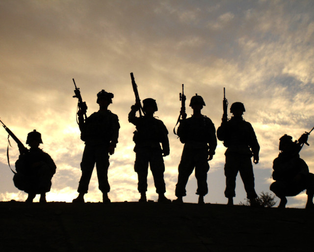 A silhouette photo of soldiers from Battery B, 3d Battalion, 320th Field Artillery Regiment, 101st Airborne Division, pose at the end of a patrol near Wynot, Iraq much like the cover of Band of Brothers.