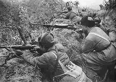 Chinese infantrymen firing from a ridge in Korea via commons.wikimedia.org