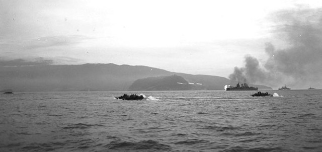 22 April 1944. US LVTs (Landing Vehicles Tracked) in the foreground head for the invasion beaches at Humboldt Bay, Netherlands New Guinea, during the Hollandia landing as the cruisers USS Boise (firing tracer shells, right center) and USS Phoenix bombard the shore. (Photographer: Tech 4 Henry C. Manger.)