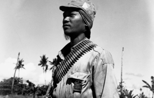 Filipino guerrilla standing with an ammunition belt around his shoulders