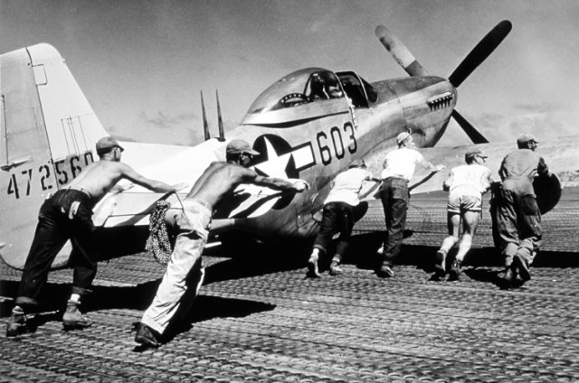 A 506th Fighter Group Mustang is pushed over pierced steel planking in the dispersal area on Iwo Jima. Note the double antenna behind the cockpit. The airplane’s “Uncle Dog” system helped Mustangs navigate over endless miles of ocean and return home. When a pilot strayed to one side of the flightpath, he heard the Morse code letter D (“dog” or “dah dit dit”). If he strayed to the other side, he heard U (“uncle” or “dit dit dah”). National Archive