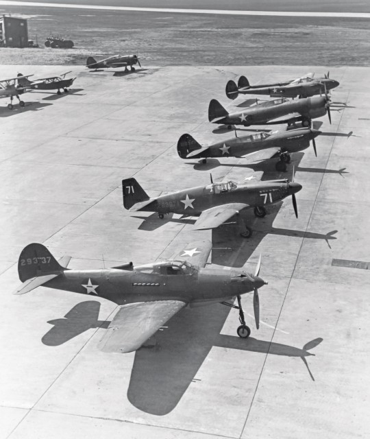 A lineup of airplanes shows all of the US Army’s fighter/attack fighter types, circa 1942. Front to back are the Bell P-39 Airacobra, NAA A-36 Apache, Curtiss P-40 Warhawk, Republic P-47 Thunderbolt, and twin-engine Lockheed P-38 Lightning. All but the “jug-nosed” P-47 flew with an Allison engine. It is interesting to see how simple and geometric the shape of the Apache/ Mustang is when compared to its counterparts. The airplane’s simple form made it relatively easy to build. National Archives 