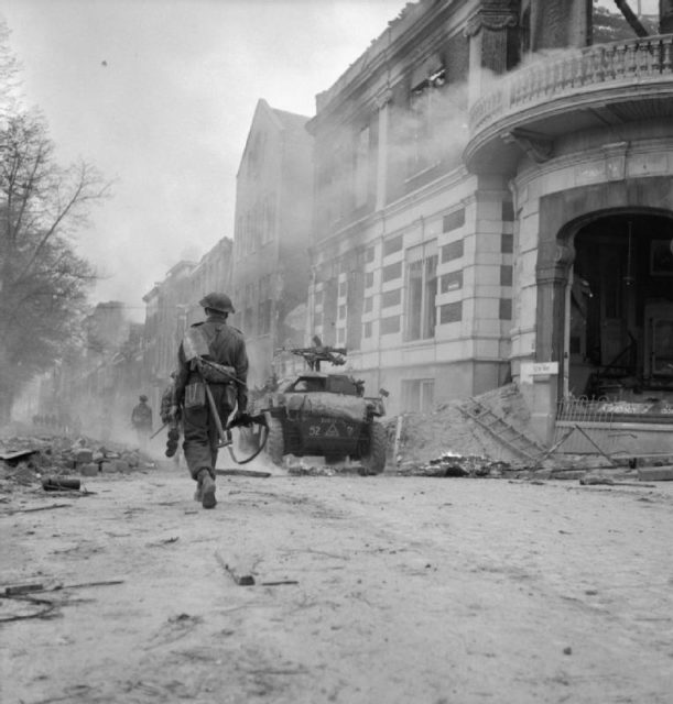 Infantry and a Humber Scout Car advance through Arnhem, 14 April.