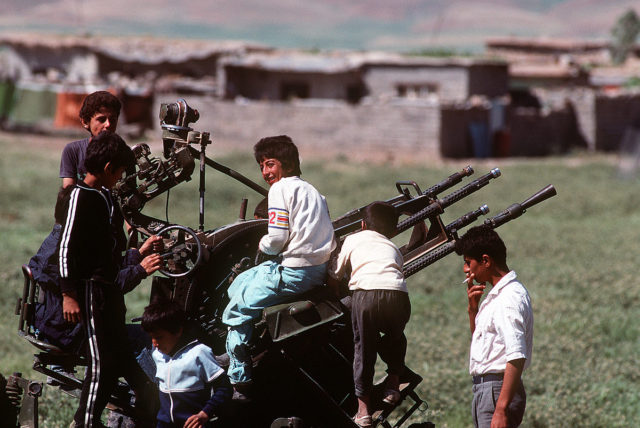Kurdish children in a refugee camp built during the U.S. and coalition Operation Provide Comfort play on a ZPU gun which was abandoned by Iraqi forces during Operation Desert Storm, 1 May 1991.