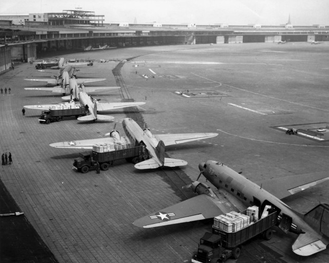 U.S. Navy Douglas R4D and U.S. Air Force C-47 aircraft unload at Tempelhof Airport during the Berlin Airlift. The first aircraft is a C-47A-90-DL (s/n 43-15672).