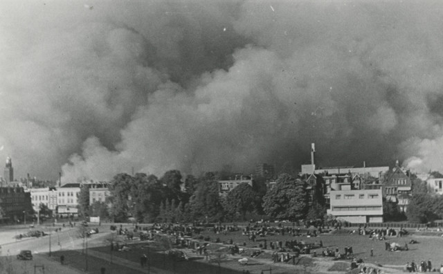 People gather on the land of Hoboken while Rotterdam burns