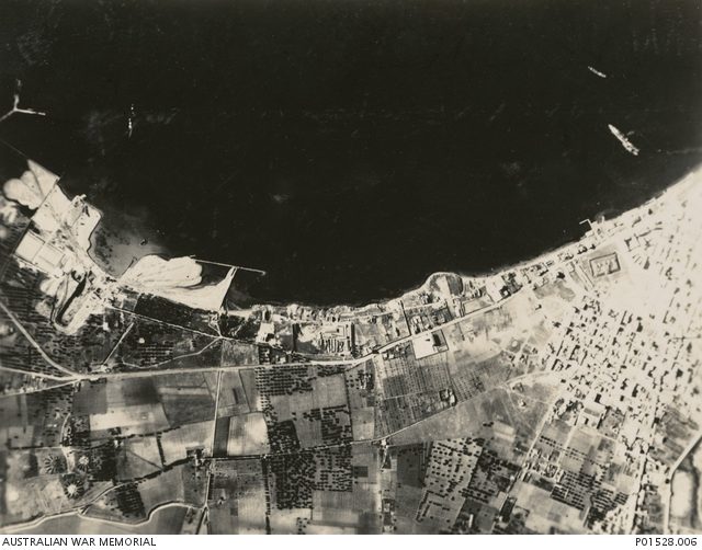 Aftermath of the battle showing an Italian battleship down by the bows and beached (far right). Photo Credit.