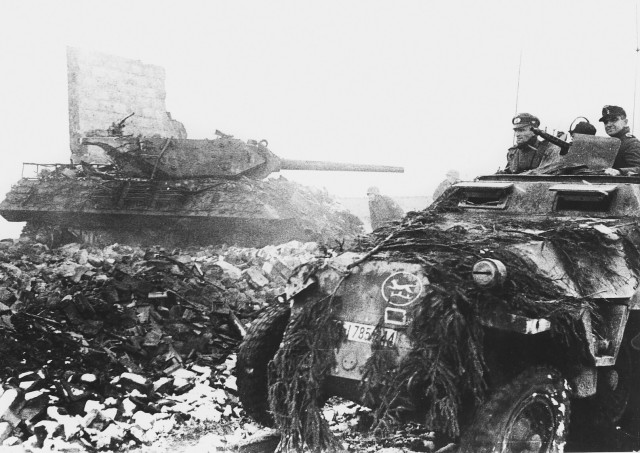 German armor and infantry of the 116th Panzer Division push past a disabled M10 tank destroyer of the 893rd Tank Destroyer Battalion (Image).