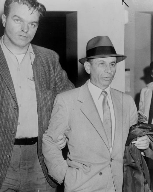 Meyer Lansky being led by detective for booking on vagrancy charge at 54th Street police station, New York City.