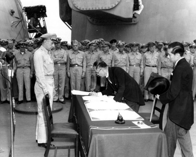 Japanese foreign affairs minister Mamoru Shigemitsu signs the Japanese Instrument of Surrender on board USS Missouri as General Richard K. Sutherland watches, September 2, 1945