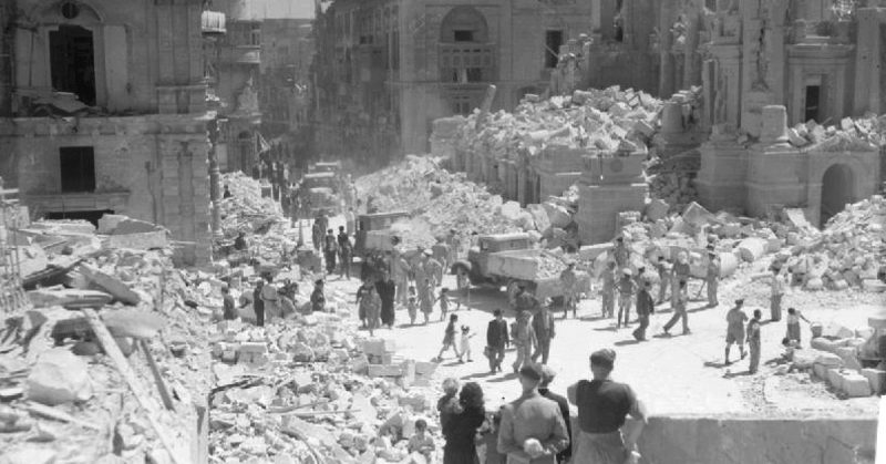 Service personnel and civilians clear up debris on a heavily bomb-damaged street in Valletta, Malta on 1 May 1942.