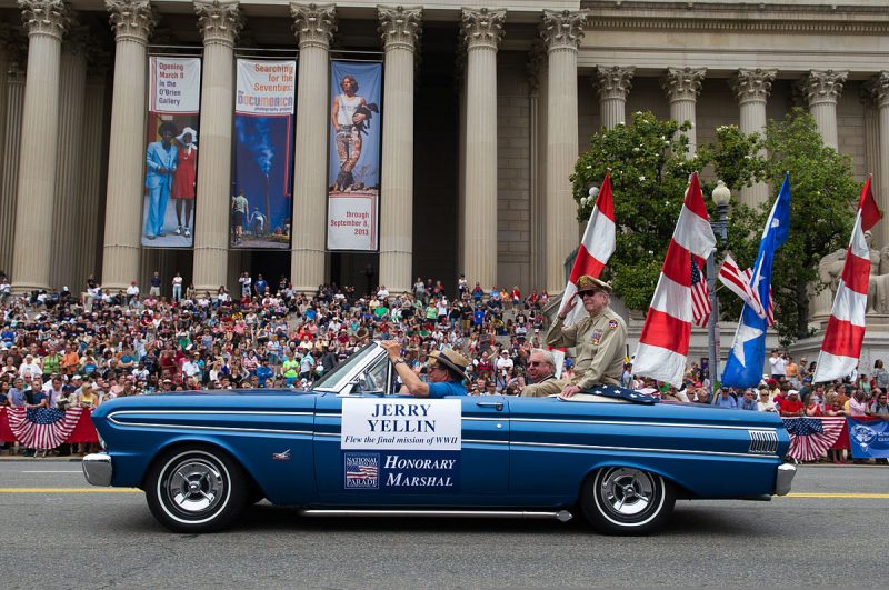 World War II veteran Jerry Yellin sits atop the back of a convertible car while serving as an honorary marshal for the 2013 National Memorial Day Parade in Washington, D.C., May 27, 2013.  Source: Wikimedia Commons/ Public Domain