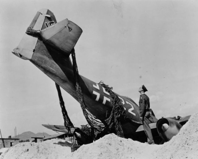 US Staff Sergeant inspects an overturned German fighter Me-262A-1a bearing the number "22 White" from the 44th Fighter Group (Jagdverband 44, JV 44). The group is a special fighter unit and manned by the best fighter pilots of the Luftwaffe during the last months of World War II.