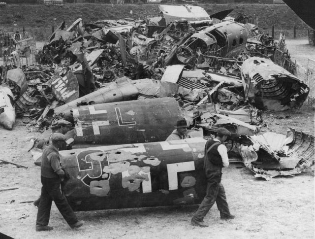Workmen carry part of the bullet-riddled fuselage of a Dornier Do 17, alongside the wreckage of other crashed German aircraft at a scrapyard in Britain, August 1940. [© IWM (HU 104718)]