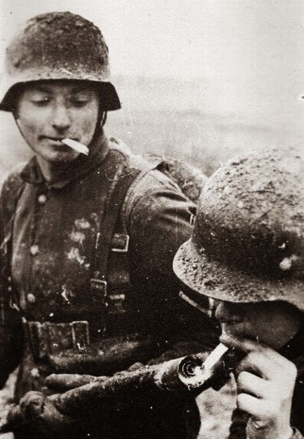 German soldier lighting his cigarette with a flamethrower [Public Domain]