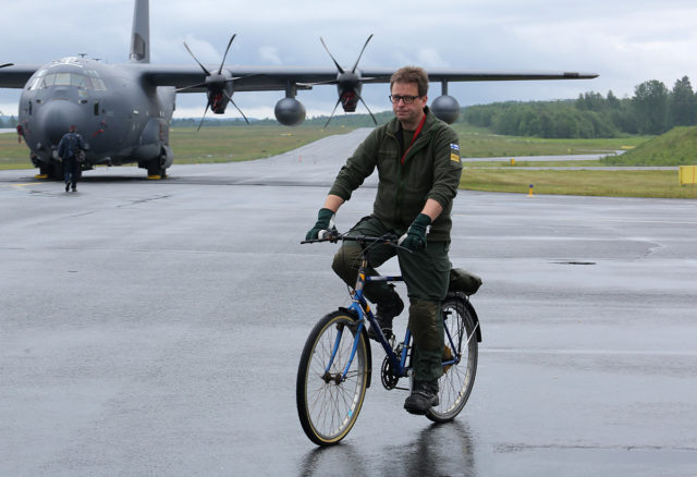 Finnish military man at bike and US Air Force Lockheed Martin MC-130J Hercules (L-382) at Tour-de-Sky airshow at Kuopio, Finand. (Photo by Fyodor Borisov/Transport-Photo Images)