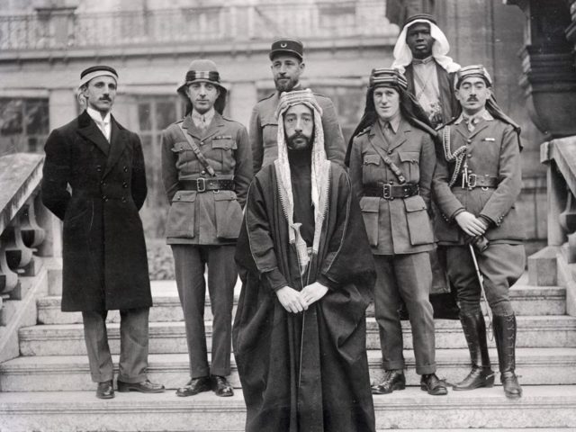Emir Faisal's party at Versailles, during the Paris Peace Conference of 1919. Left to right: Rustum Haidar, Nuri as-Said, Prince Faisal (front), Captain Pisani (rear), Lawrence, Faisal's servant (name unknown), Captain Hassan Khadri.
