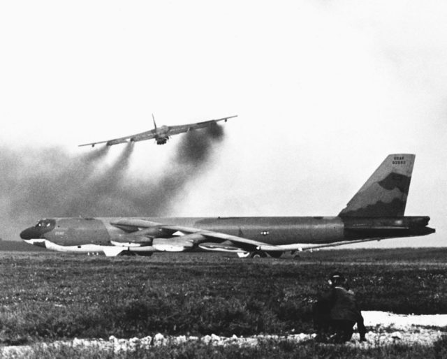 A U.S. Air Force Boeing B-52G-125-BW Stratofortress (s/n 59-2582) from the 72nd Strategic Wing (Provisional) waits beside the runway at Andersen Air Force Base, Guam (USA), as another B-52 takes off for a bombing mission over North Vietnam during Operation Linebacker II on 15 December 1972. Source: By USAF - U.S. DefenseImagery photo VIRIN: DF-SN-84-11616, Public Domain, https://commons.wikimedia.org/w/index.php?curid=10611705