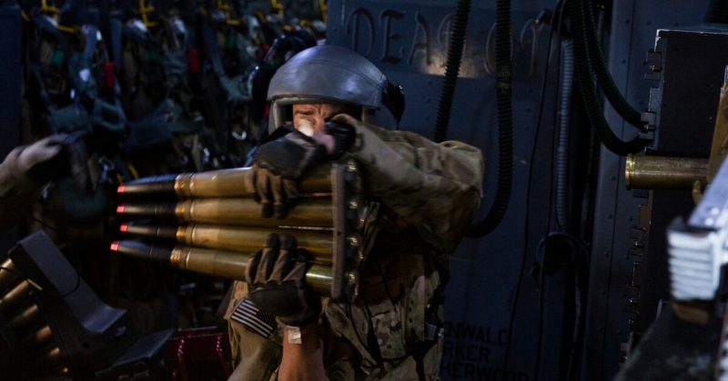 An aerial gunner with the 4th Special Operations Squadron picks up a stack of 40mm rounds.